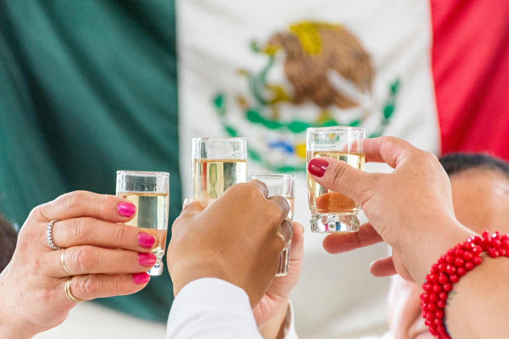 Brindis con caballitos de tequila y bandera de México